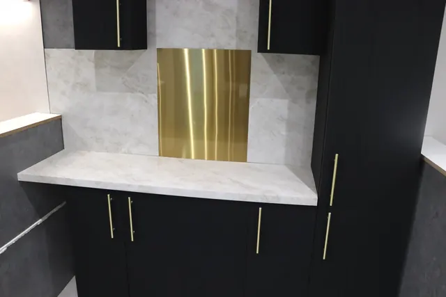 Black and gold dresser unit with a marble-effect worktop in our showroom
