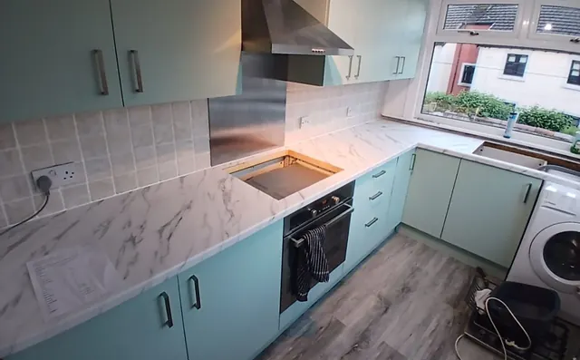 Oak kitchen wrapped in duck-egg green with marble-effect worktops