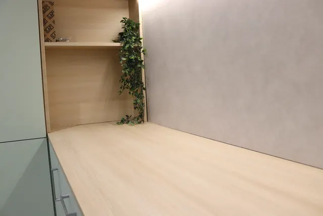 Light oak-effect wrapped worktop beside sage green units