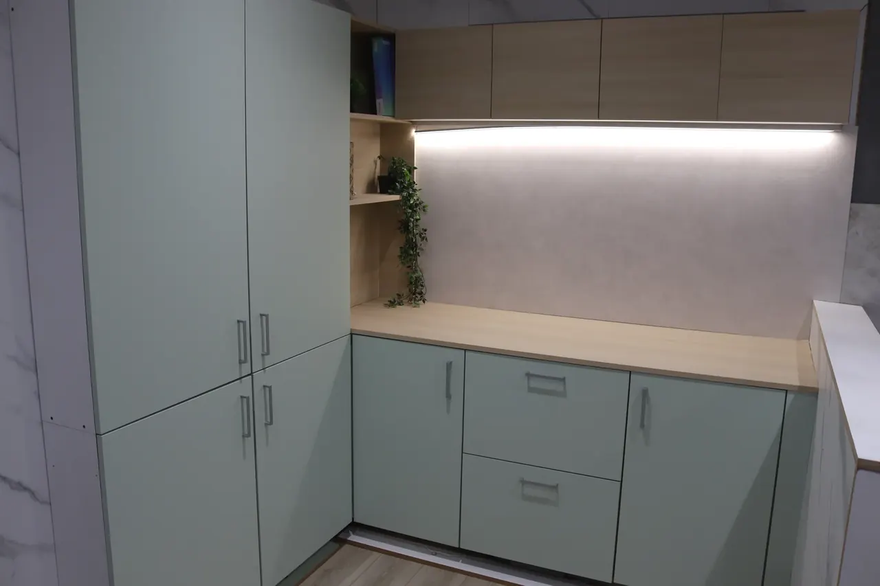 Sage green wrapped kitchen with oak-effect worktops and under-cabinet lighting in our Cambuslang showroom
