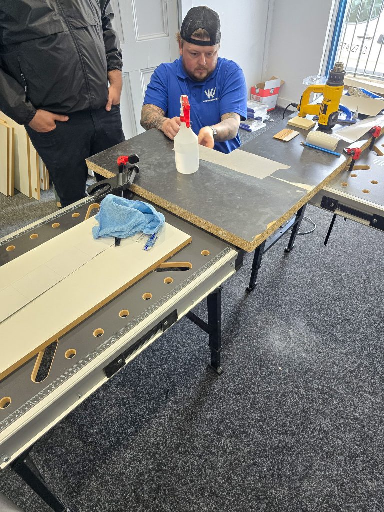 Trainee cleaning and prepping a door panel before wrapping