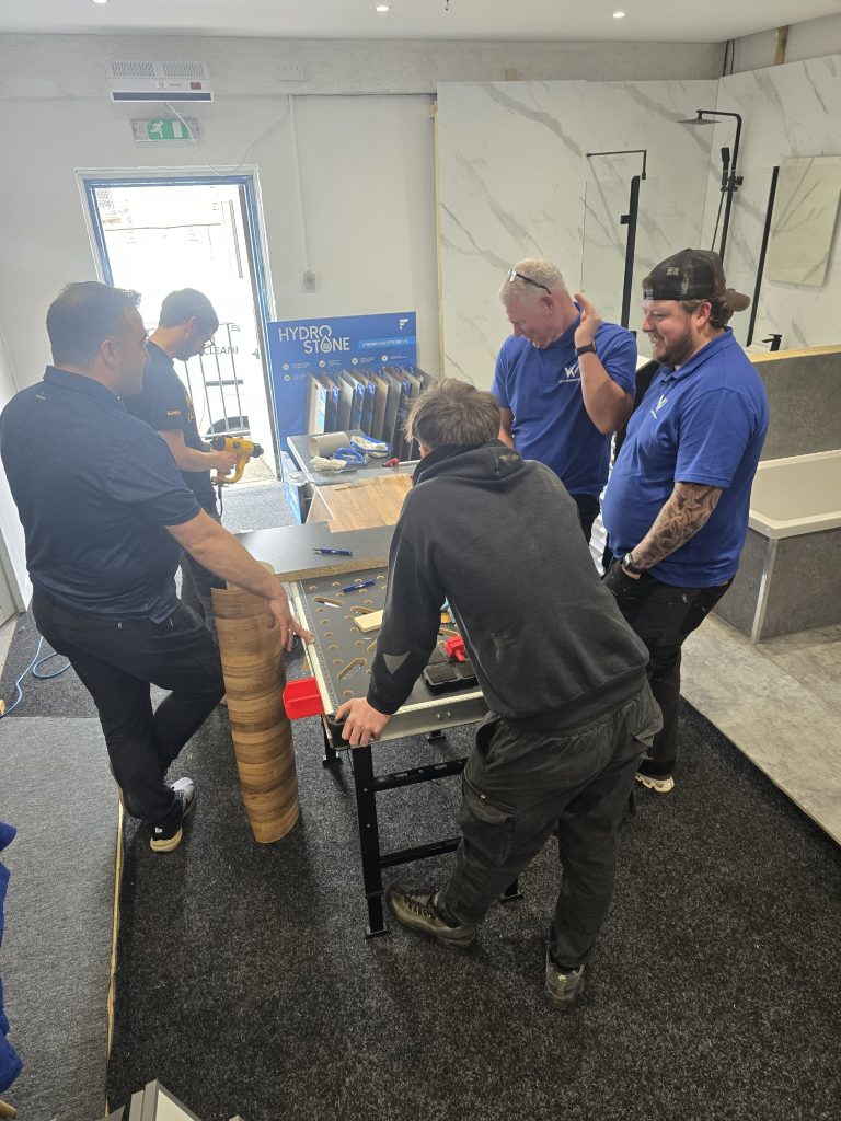 The group gathered round the workbench with a roll of wood-effect wrap