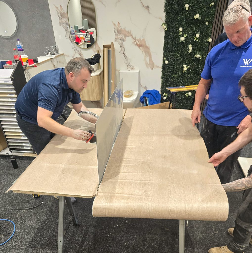 Laying a sheet of wrap onto a panel during the Kitchen Wrapper training course